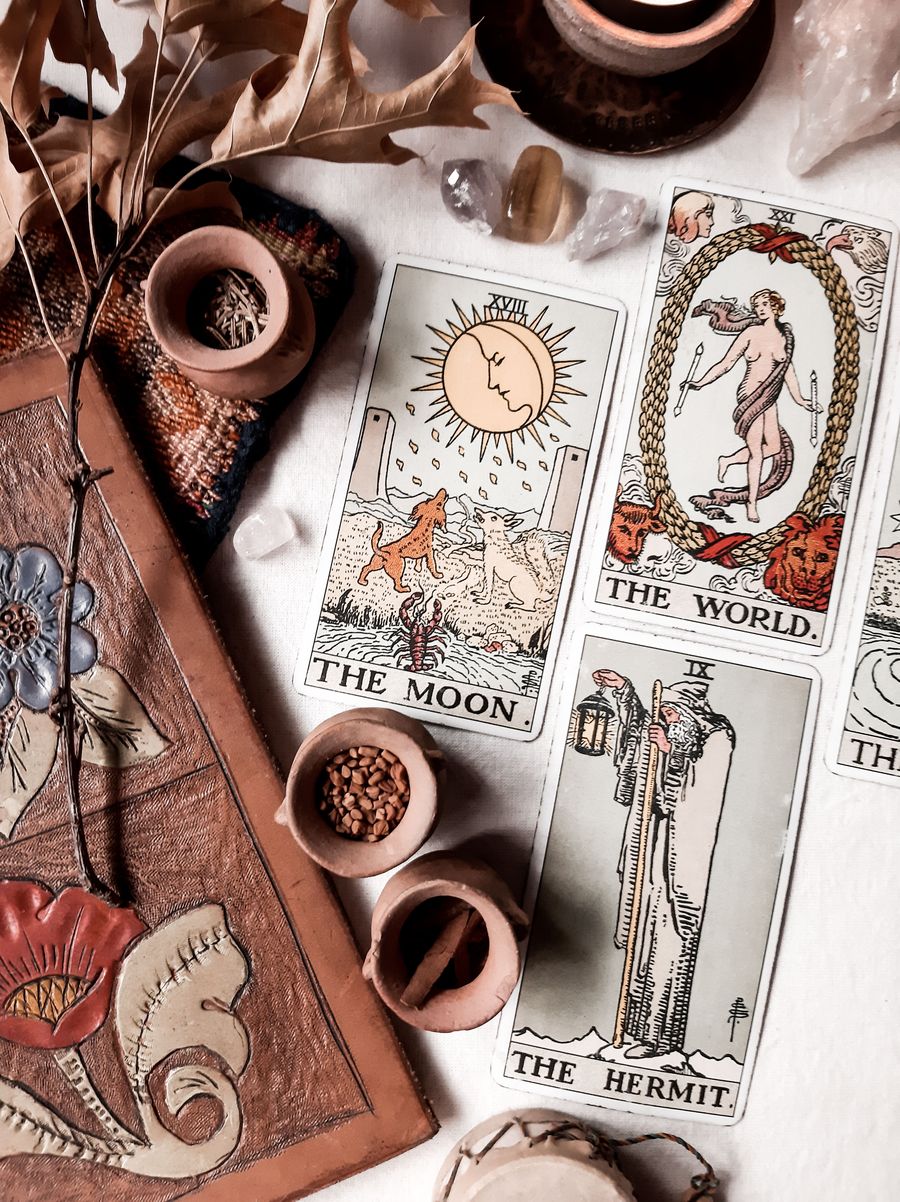 Cartas de la Luna, el Mundo y el Ermitaño junto a cuencos de cerámica
